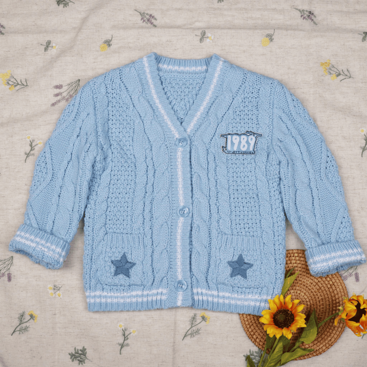 Blue knitted cardigan with star designs on a floral-patterned fabric background