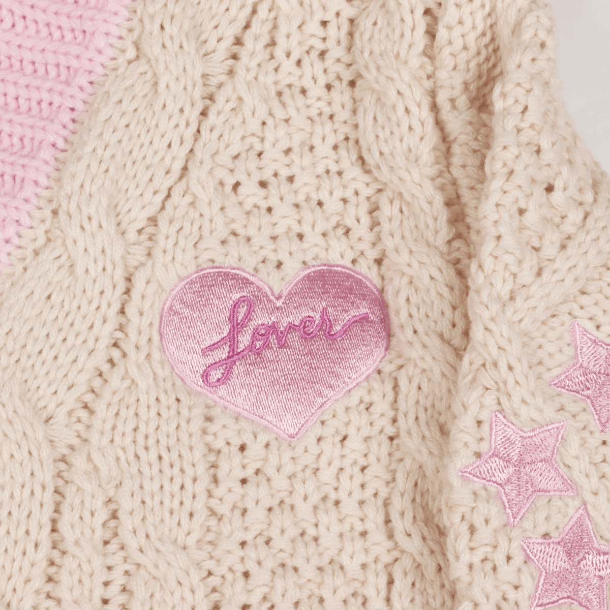 Pink heart-shaped patch with 'Love' text on a knitted fabric background