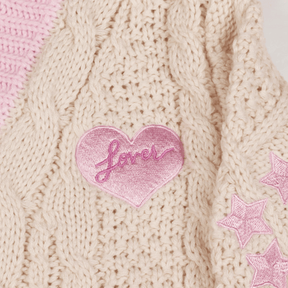Pink heart-shaped patch with 'Love' text on a knitted fabric background