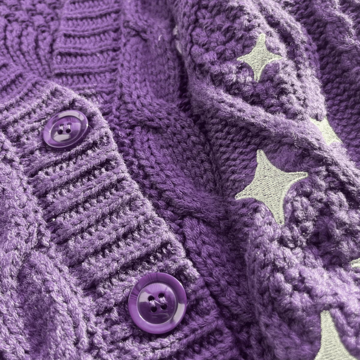 Close-up of a purple textured fabric with star patterns and buttons.