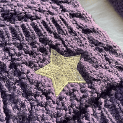 Close-up of a purple textured fabric with a yellow star embroidered on it.