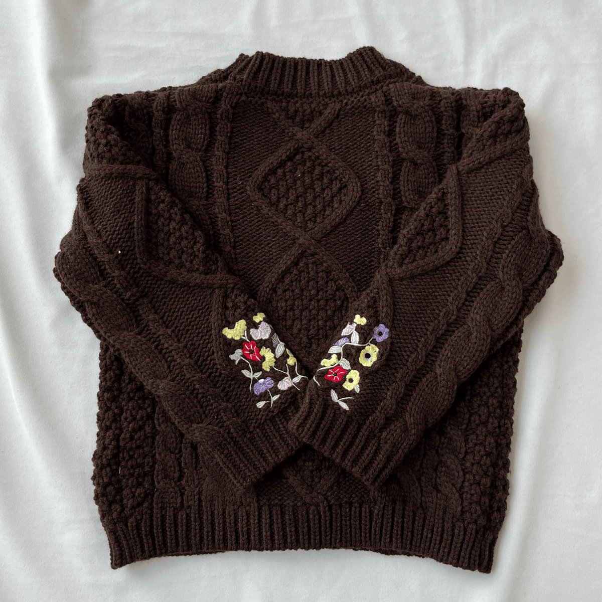 Brown knitted sweater with floral embroidery on a white background